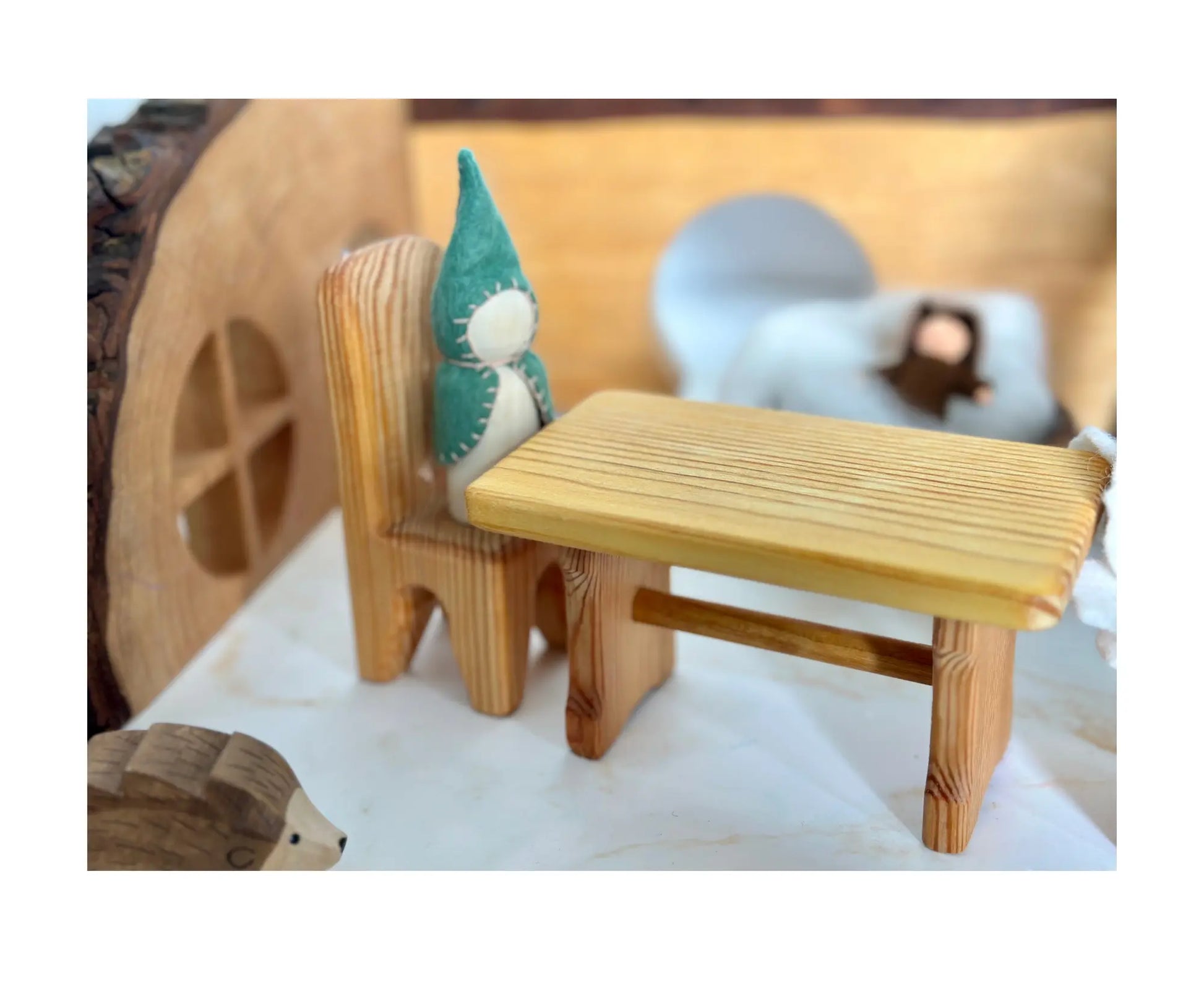 Wooden dollhouse table and chairs arranged in a small-world play scene with natural wood furniture