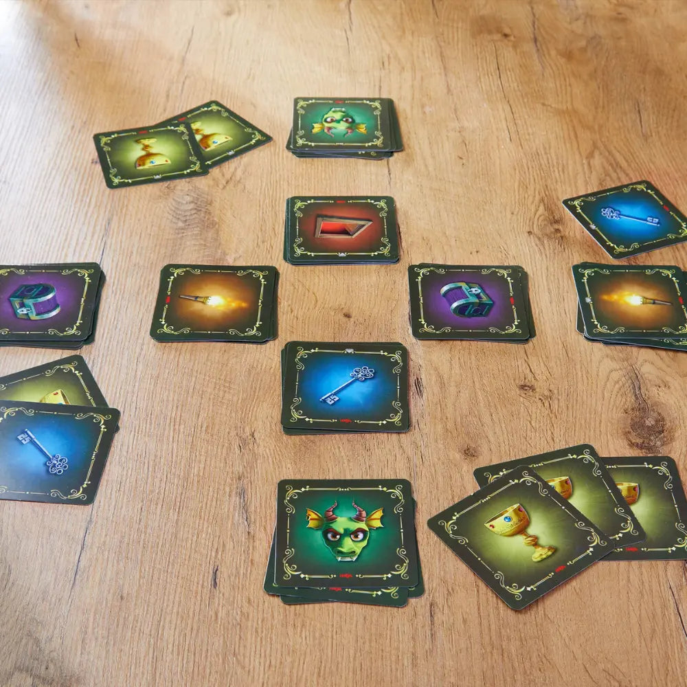 Strategy card game for kids and families on a wooden top table with gold goblet, green dragon, treasure chest, and key cards