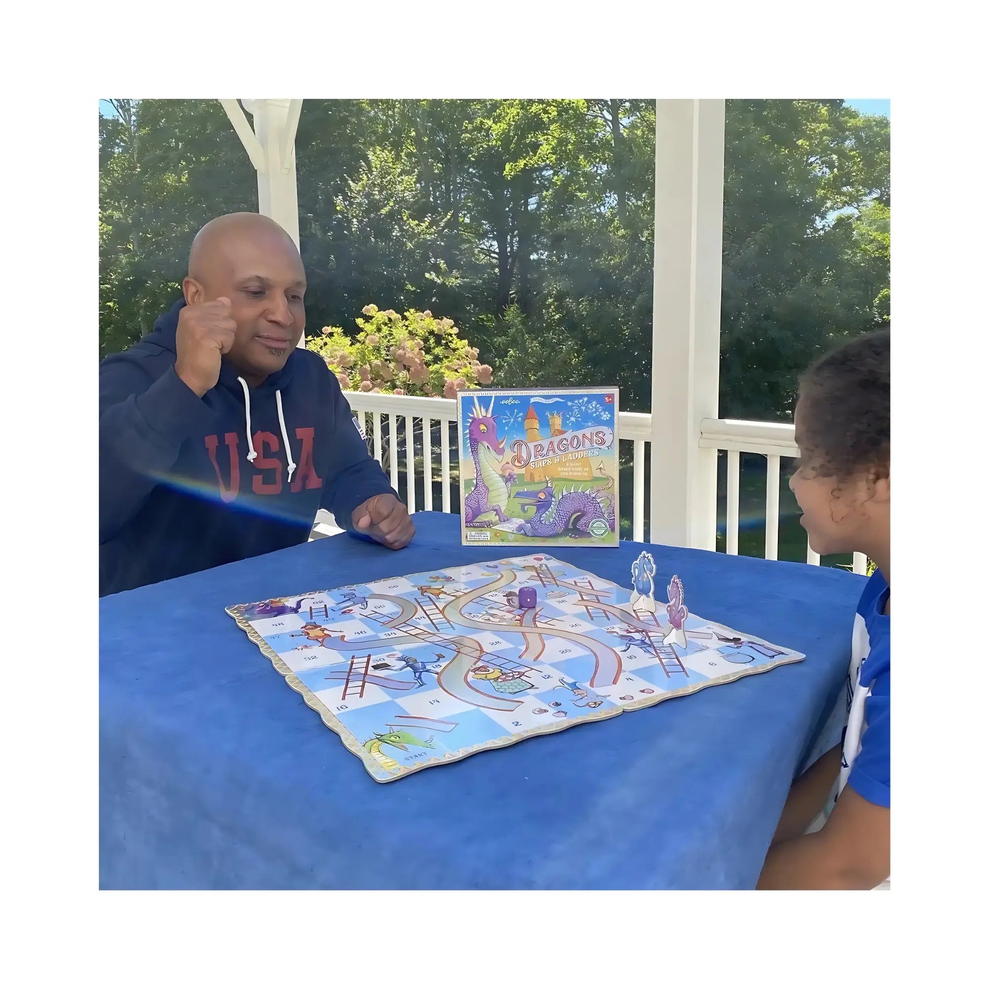 Adult and child playing the Dragons Slips & Ladders board game together at a table.