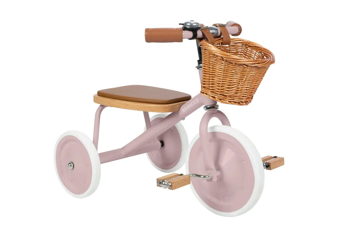 Pink children's tricycle with a wicker basket on a white background