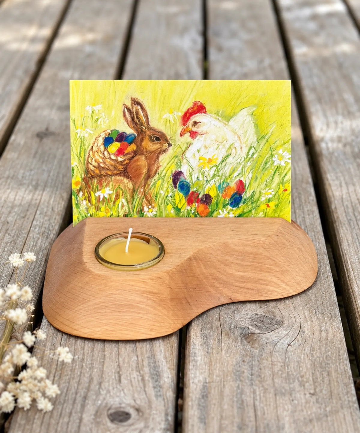 Easter Eggs postcard by Marjan van Zeyl displayed in a wooden card and candle holder on a weathered wood table.
