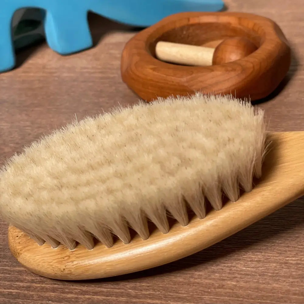 Wooden baby hair brush with natural bristles on a wooden surface
