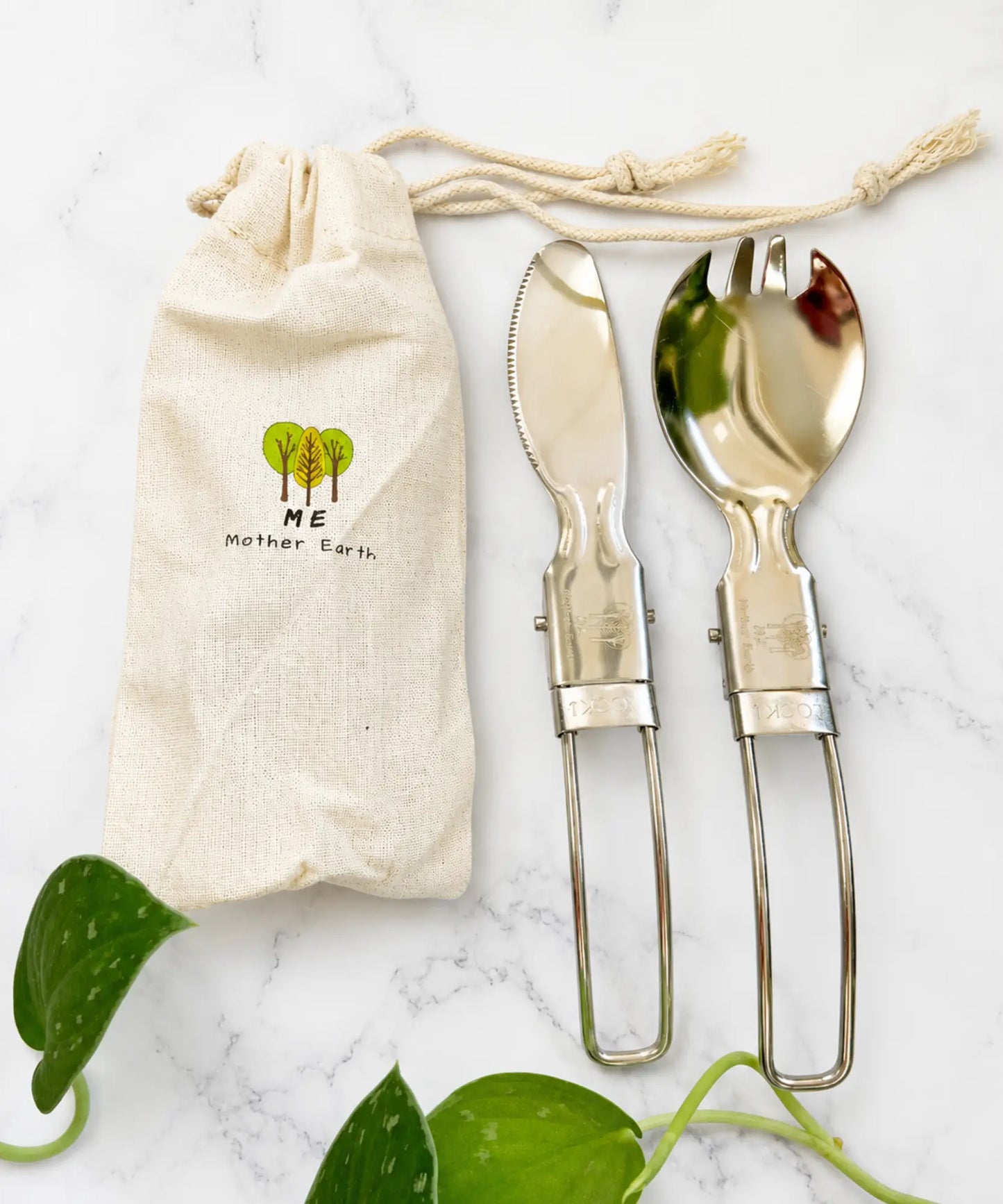 Set of silver cutlery with a drawstring bag labeled 'Mother Earth' on a marble surface.