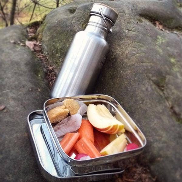 ECOlunchbox Solo Cube packed with a sandwich, vegetables, and snacks beside a reusable water bottle