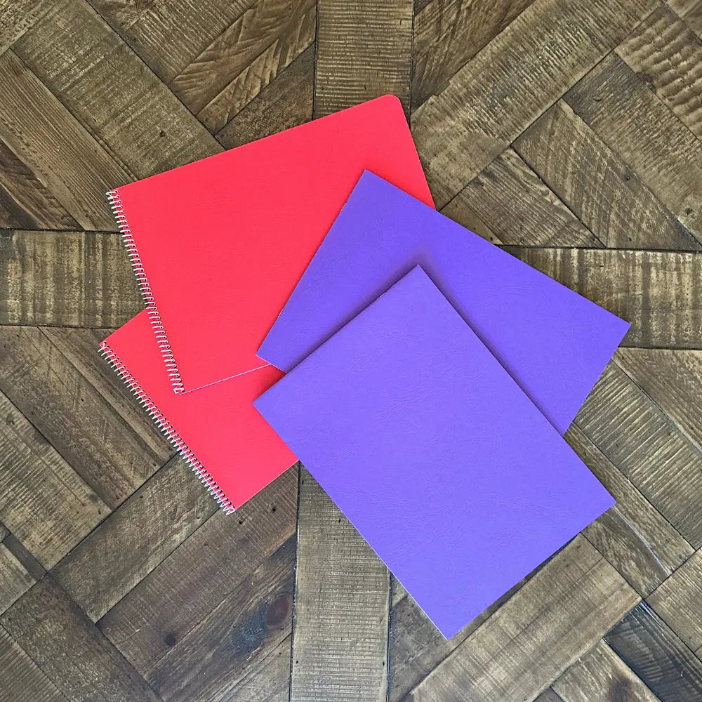 Red and purple music notebooks on a wooden floor