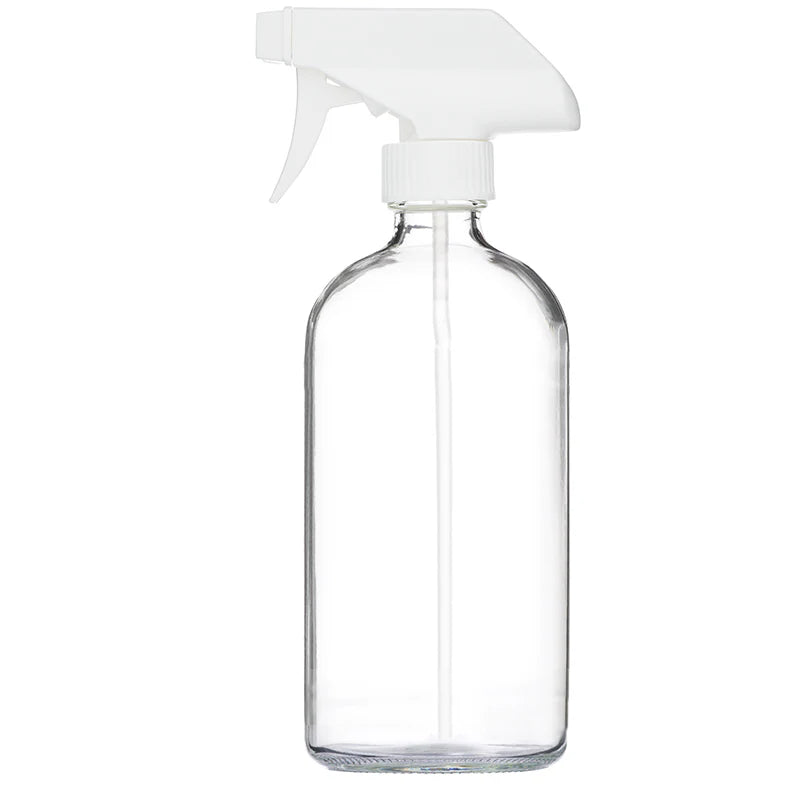 An empty clear glass spray bottle with a white sprayer top.