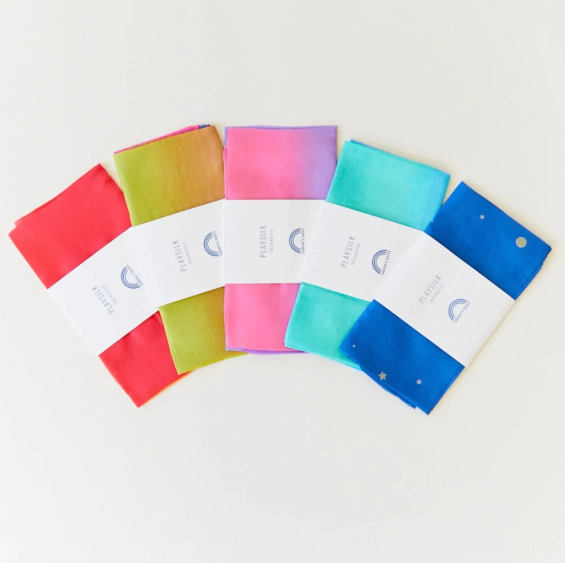 Enchanted Playsilk color ways in fire, blosoom, rainbow, sea, and starry fanned out on light background