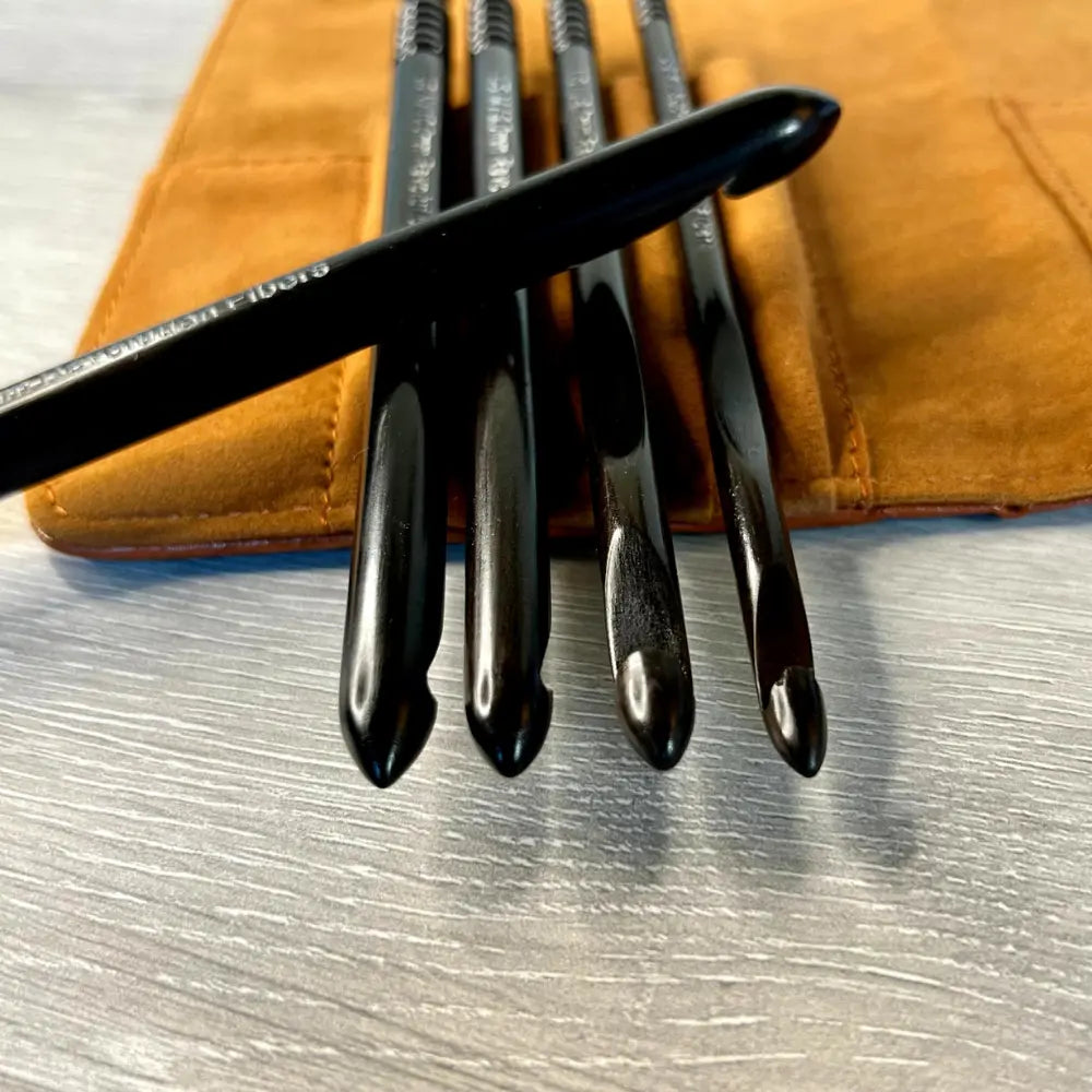 Set of black makeup brushes on a brown leather case with a metallic surface background