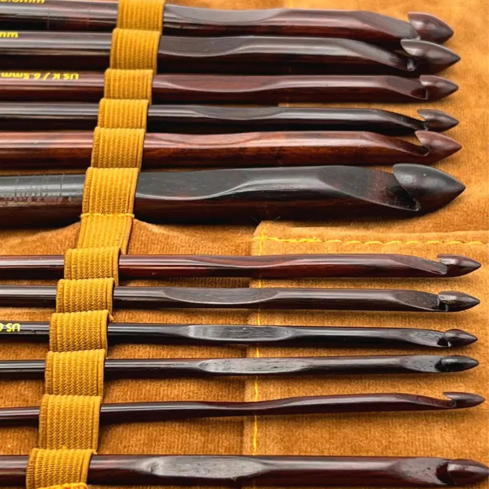 Set of crochet hooks with wooden handles on a yellow strap against an orange background