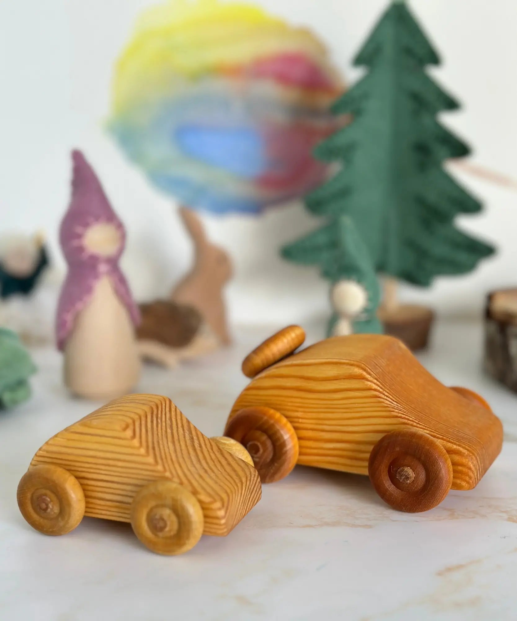 Two wooden toy cars on a surface with decorative items in the background.
