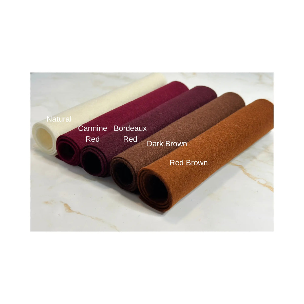 100% Wool Felt rolls on a marble surface in natural, carmine red, bordeaux red, dark brown, and red brown