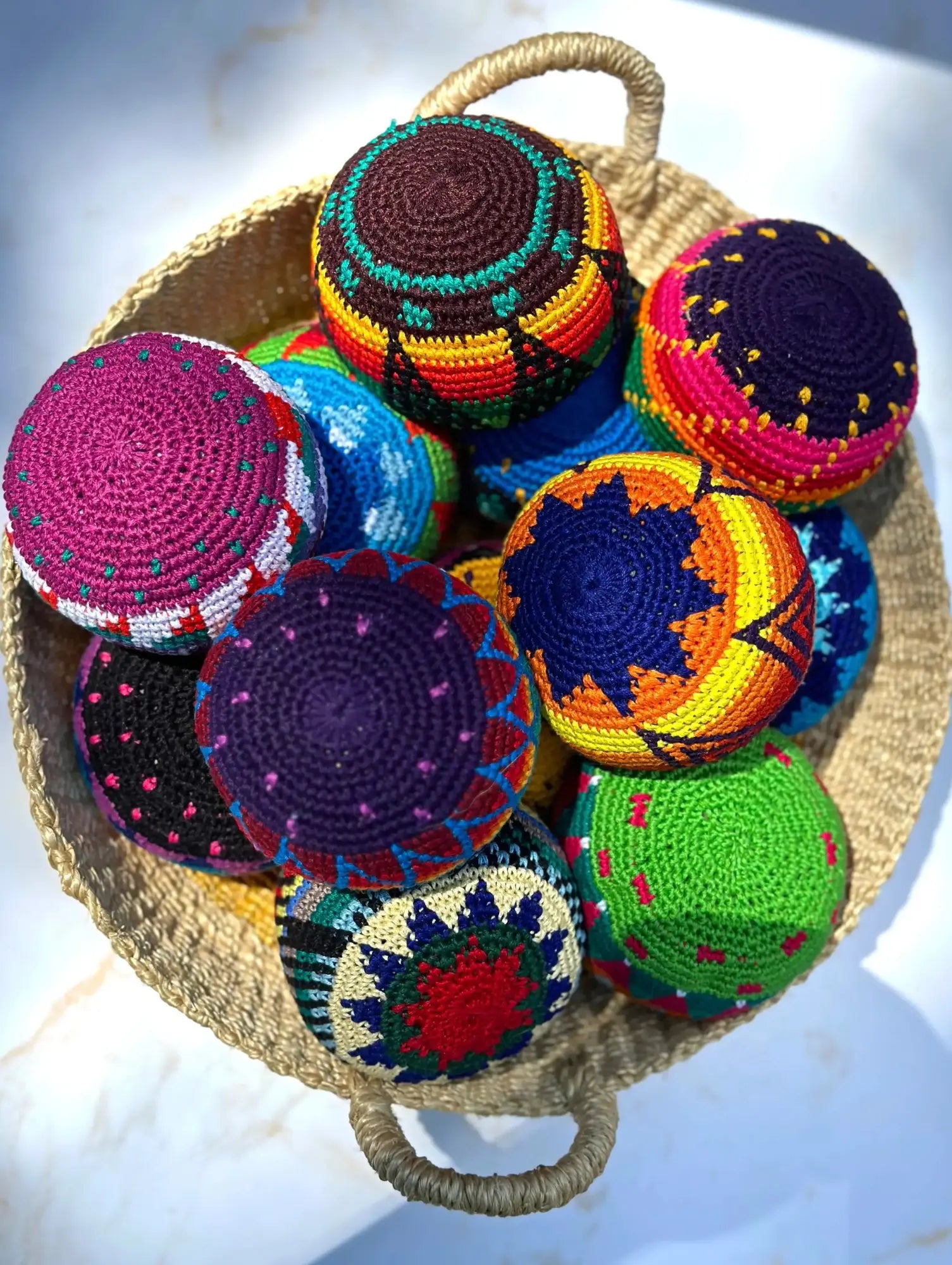 Colorful crocheted balls in a woven basket on a light background