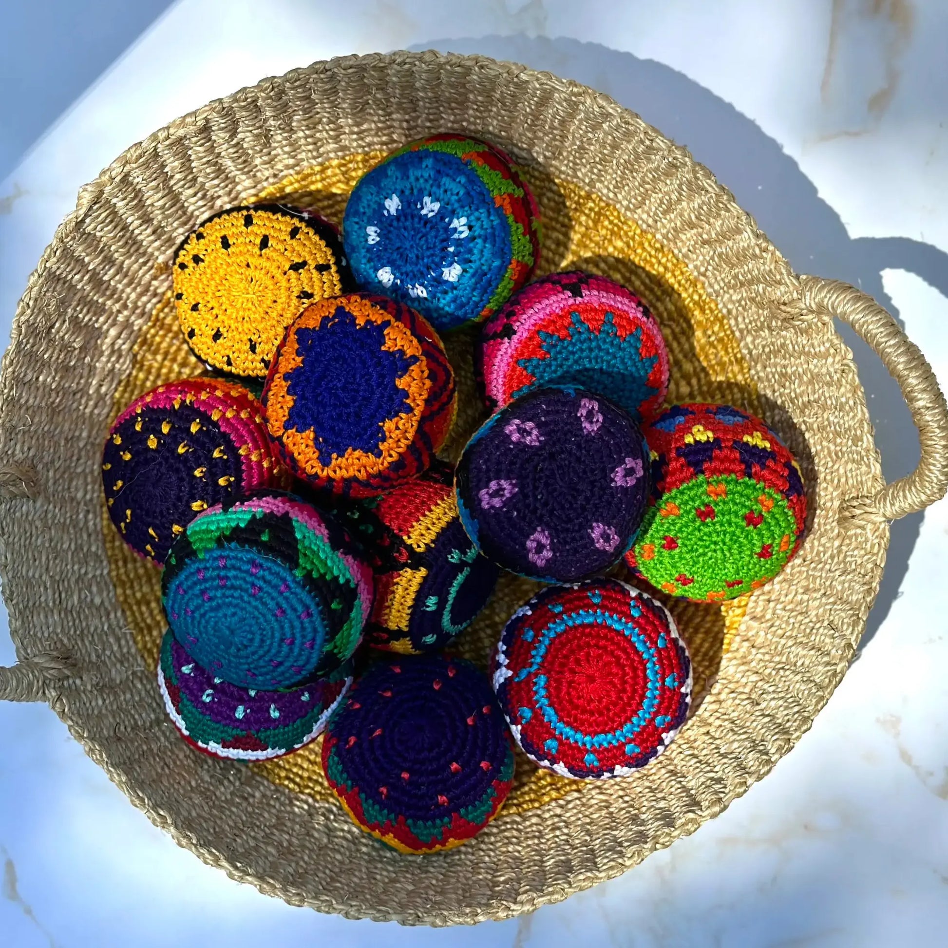 Colorful crocheted hacky foot sacks in a woven basket on a light background
