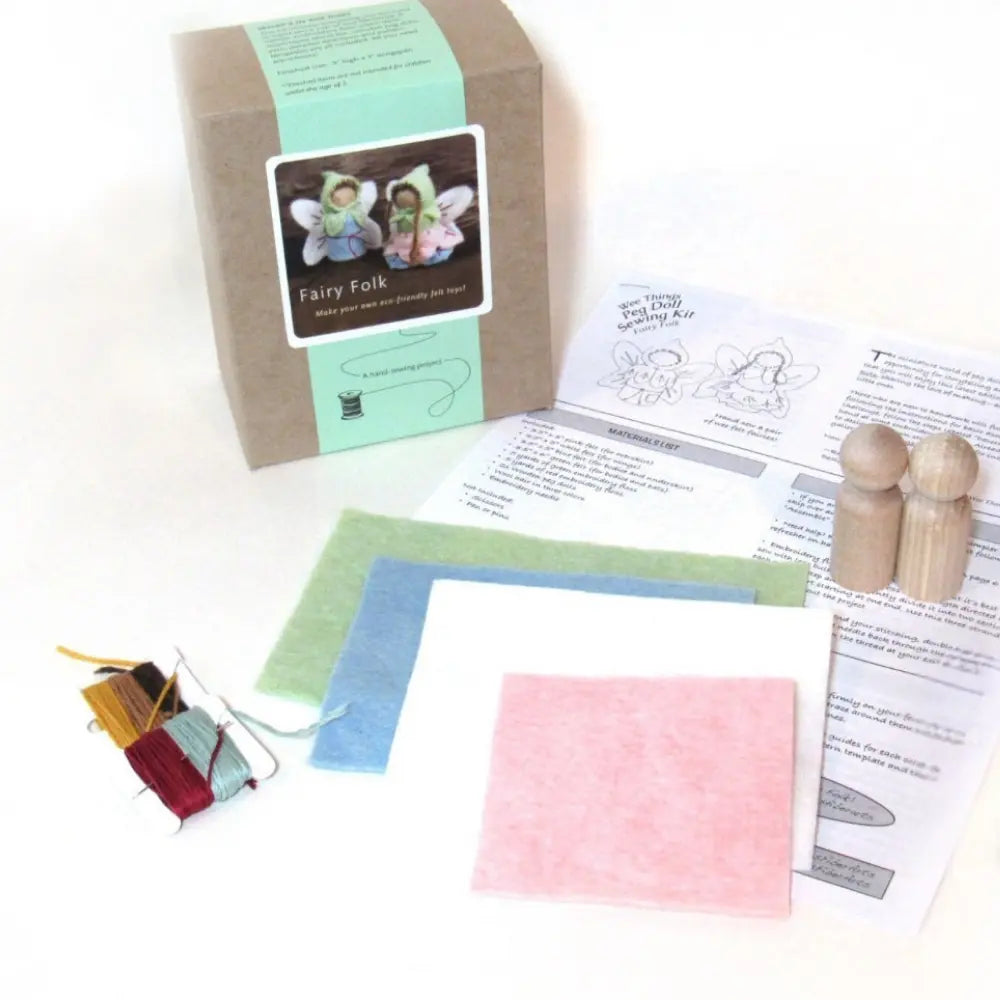 Fairy Folk craft kit with wooden figures, fabric, and instructions on a white background
