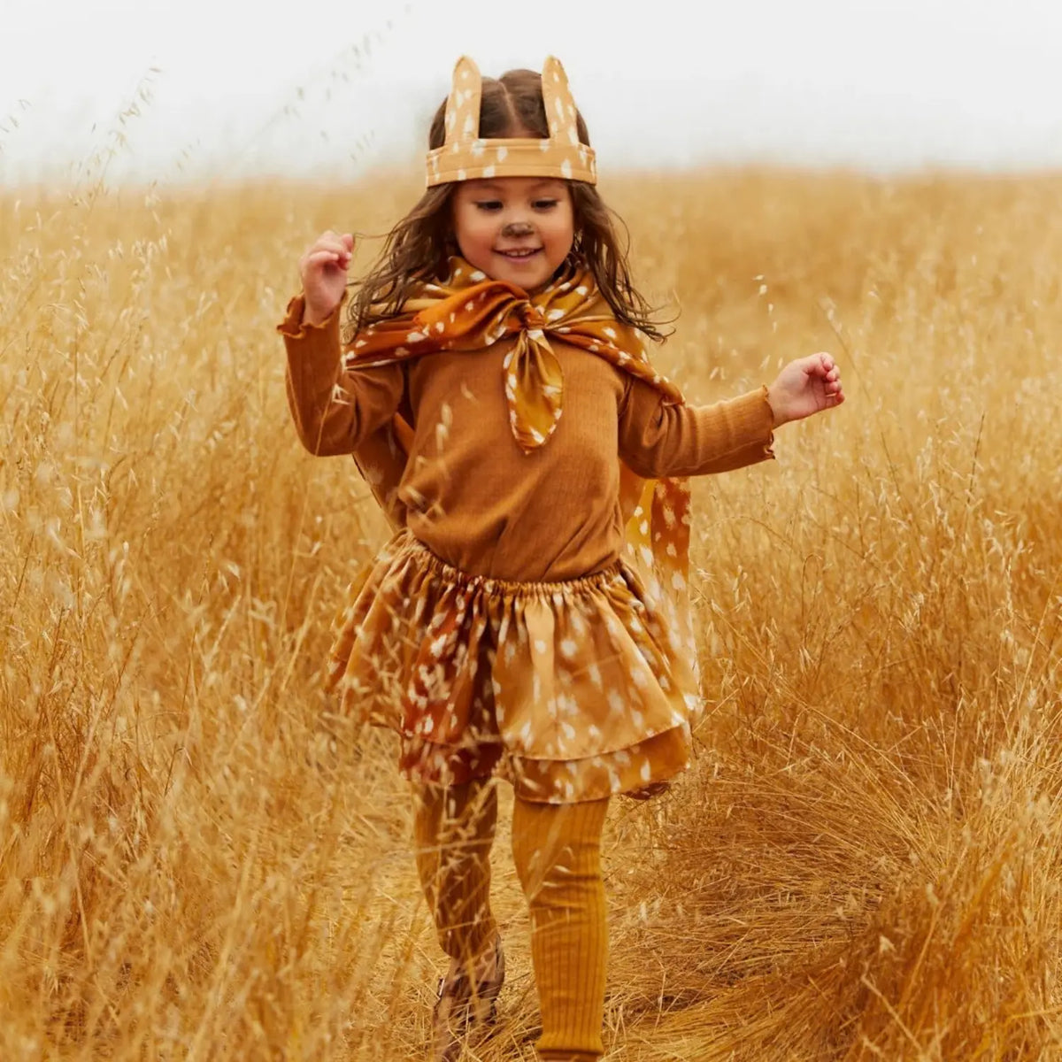Child wearing a fawn-print Playsilk as a cape with matching fawn ears