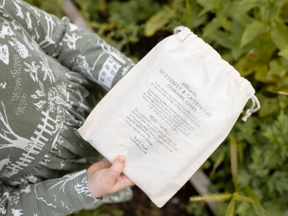 a child holding a drawstring cloth bag that says Butterfly and Caterpillar Learning Cards