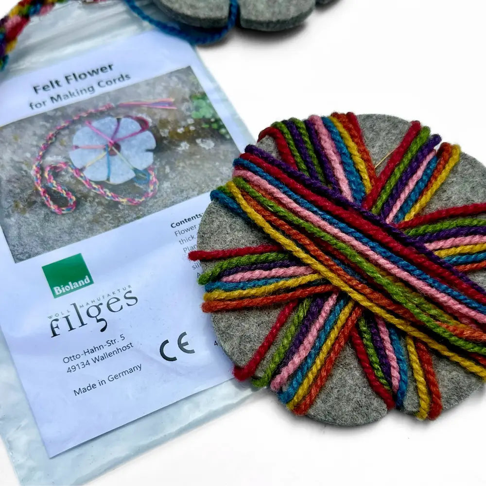 Colorful yarn on a felt coaster with filges branding and a product card.