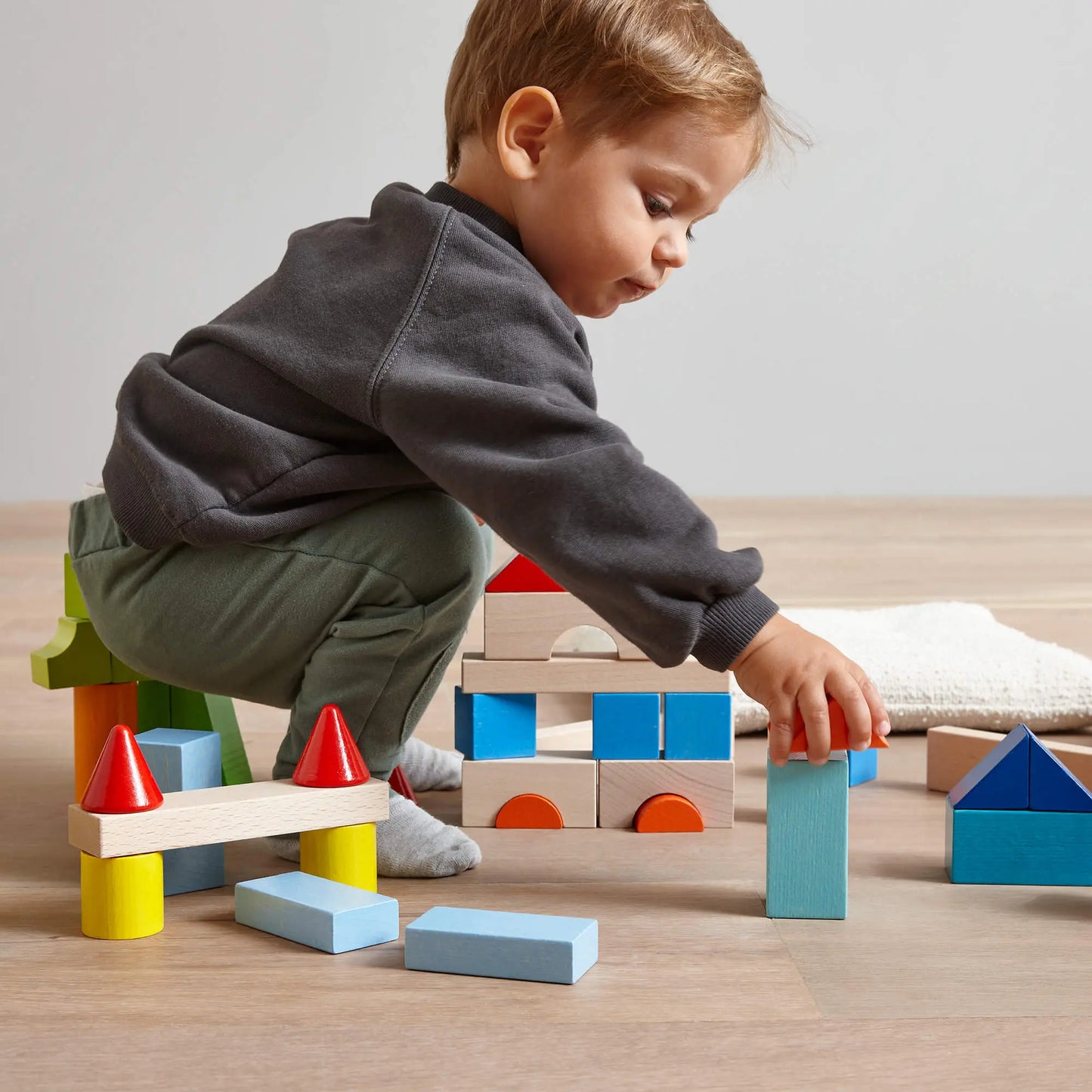 Child playing with colorful building blocks on a wooden floor