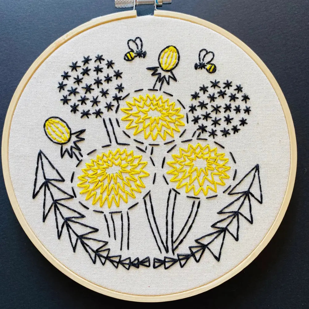 Finished Bee Kind dandelion embroidery hoop art with bees and geometric leaves