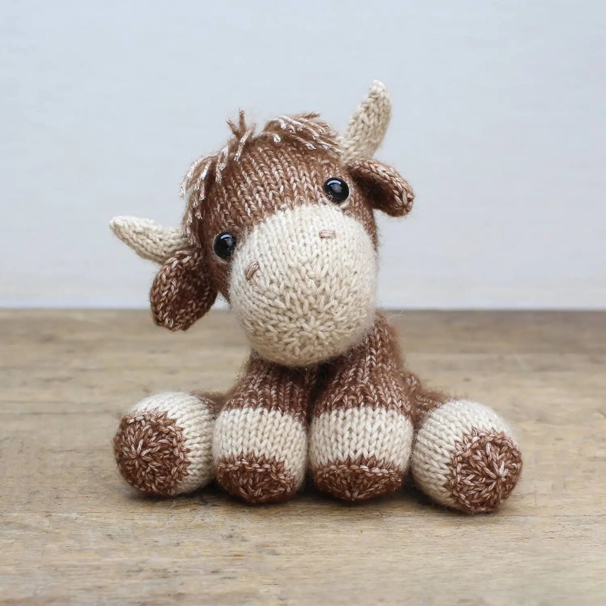 Finished Luke Highlander knitted Highland cow with cream horns, brown yarn, and safety eyes