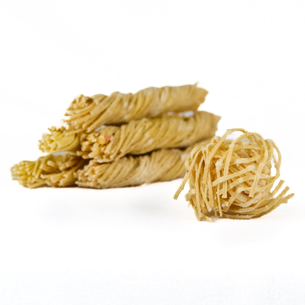 Piles of beeswax soaked wick firestarters on a white background