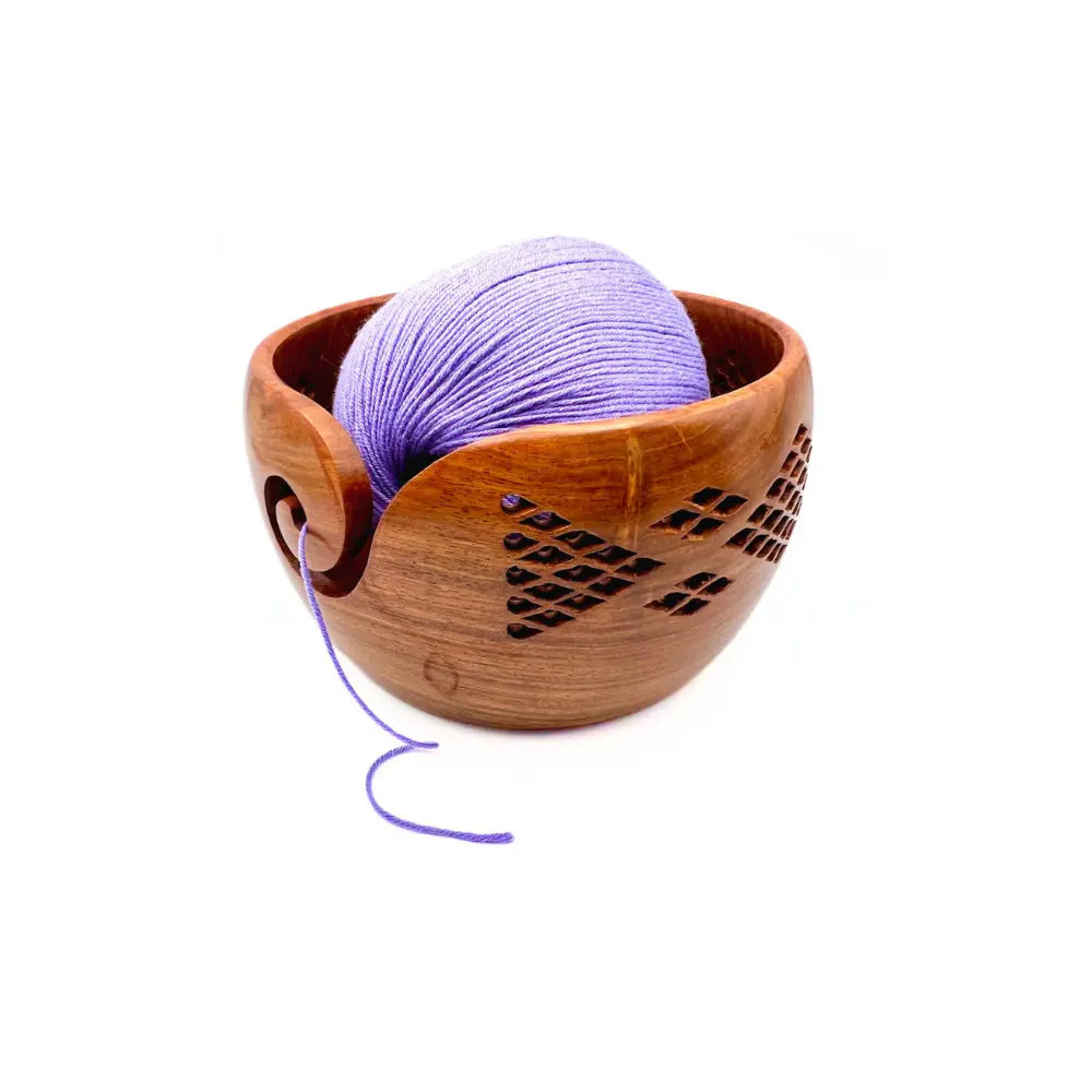 Wooden yarn bowl with a ball of purple yarn on a white background