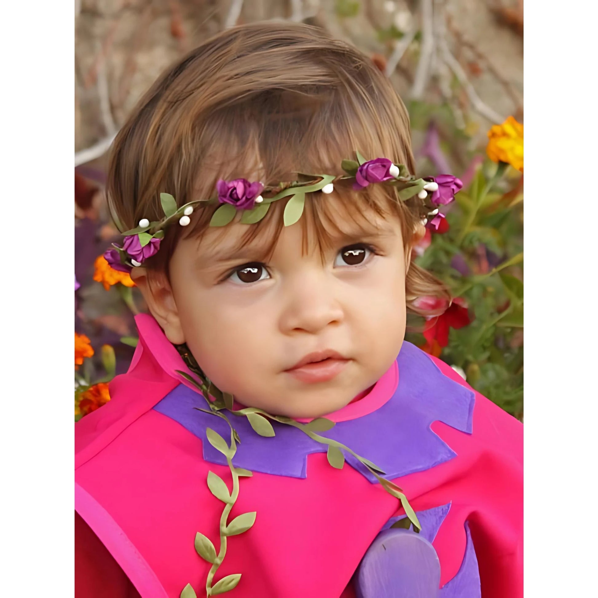Child wearing a purple flower crown with green leaves on an outdoor background