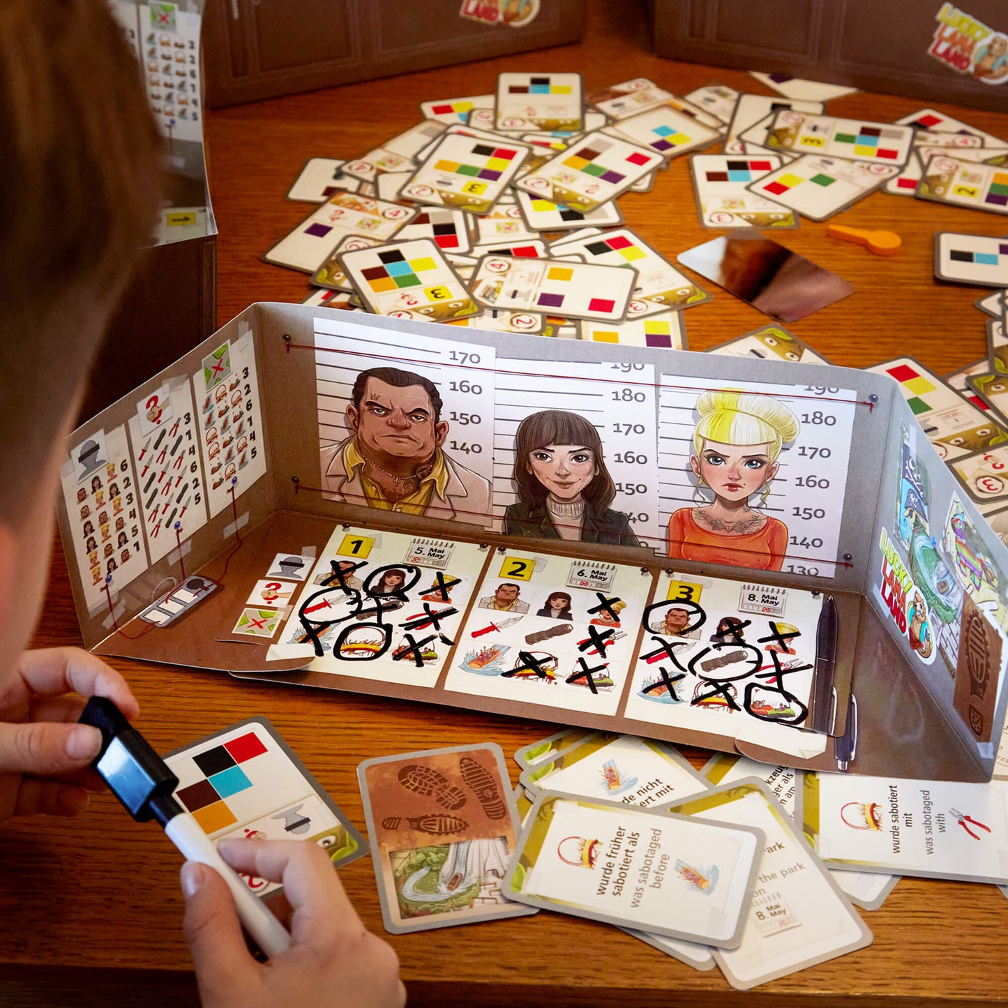 Board game with character cards and a player using a light pen on a wooden table.