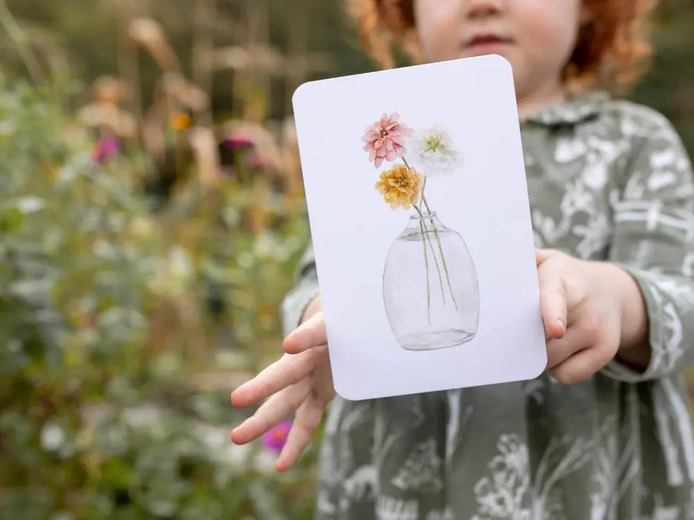 Child holding garden alphabet card with flower illustration