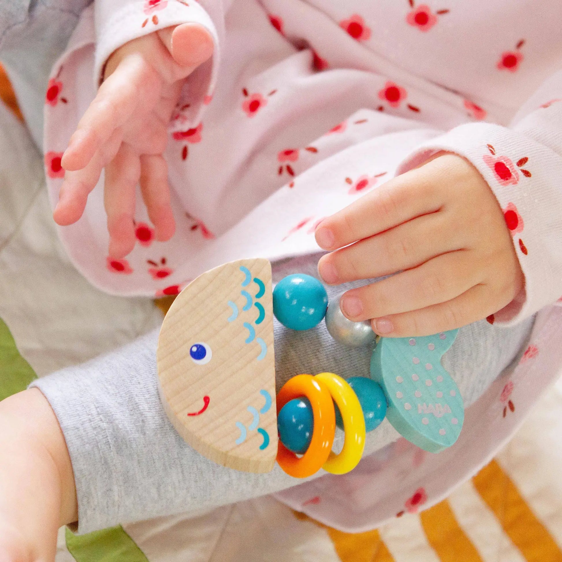 Child's hand holding a colorful wooden toy with colorful beads