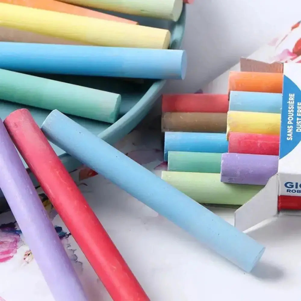 Assorted colorful chalks on a white surface with a box of chalks in the background.