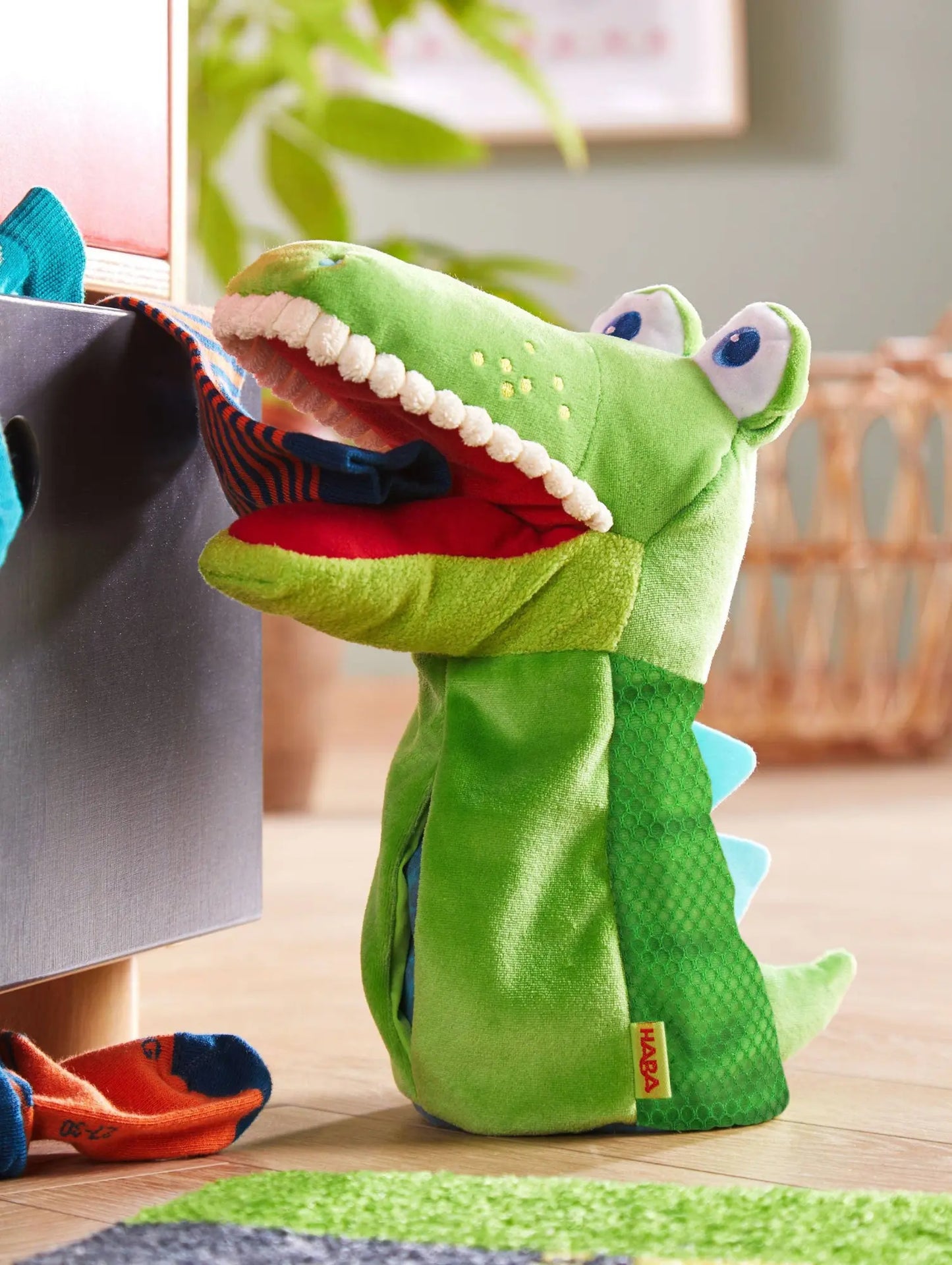Green crocodile eat-it-up hand puppet with a red mouth inside a house setting