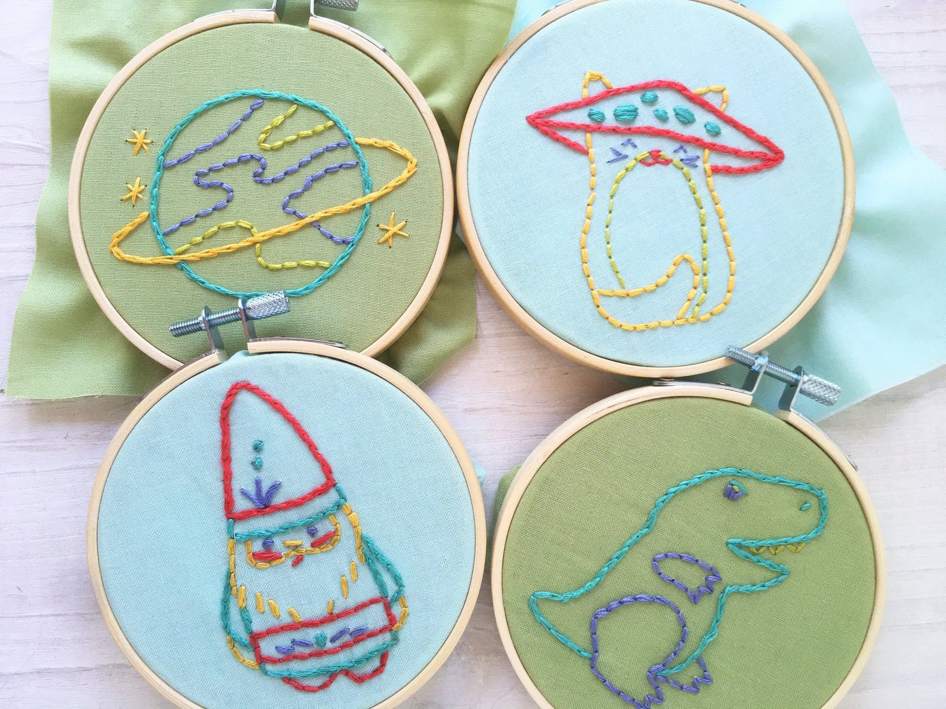 Four embroidered hoops with space-themed designs on a light background