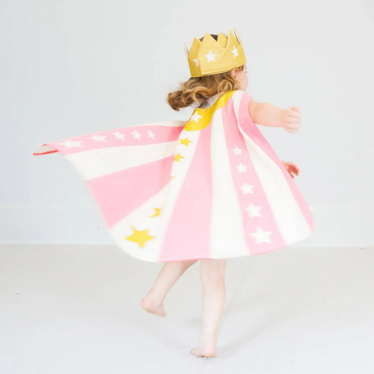 Child wearing a gold star crown with a pink storybook dress-up cape