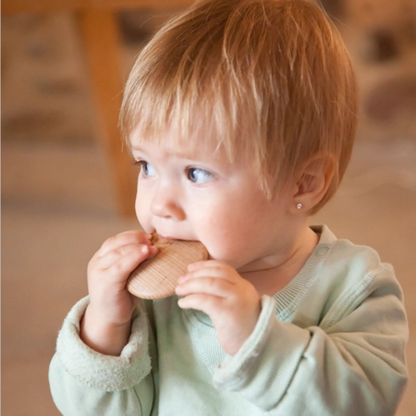 Child holding a Grapat wooden disc indoors