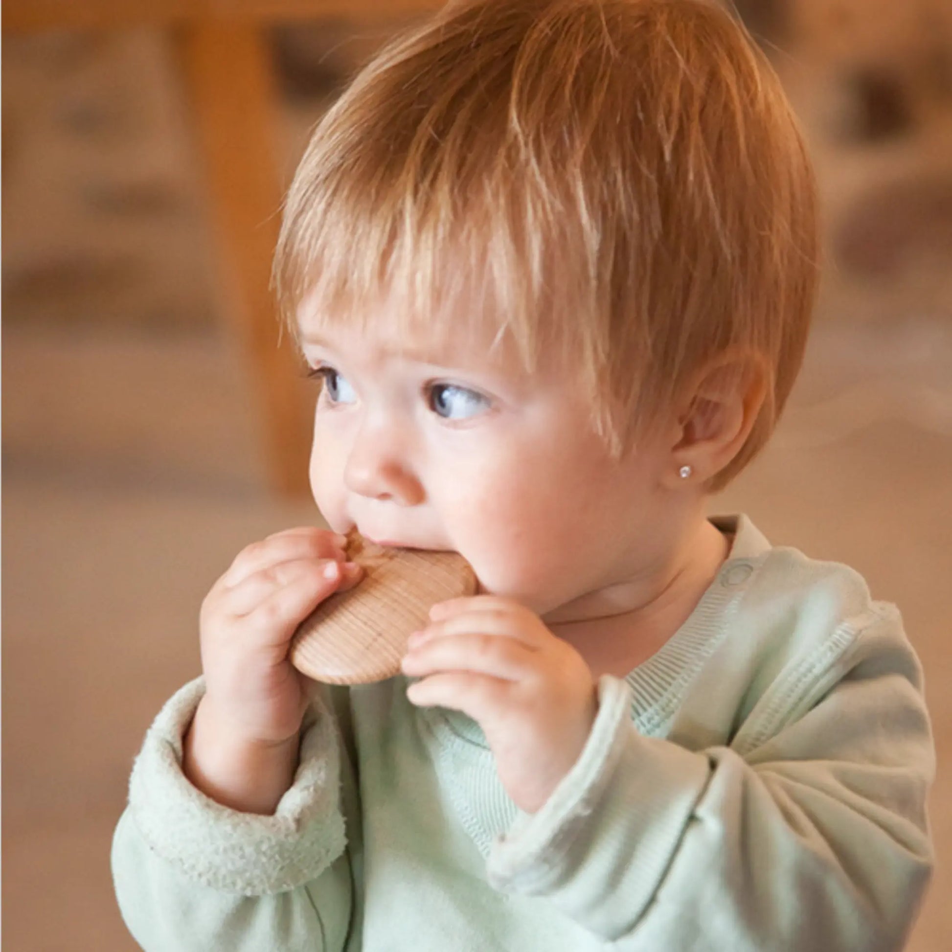Child holding a Grapat wooden disc indoors