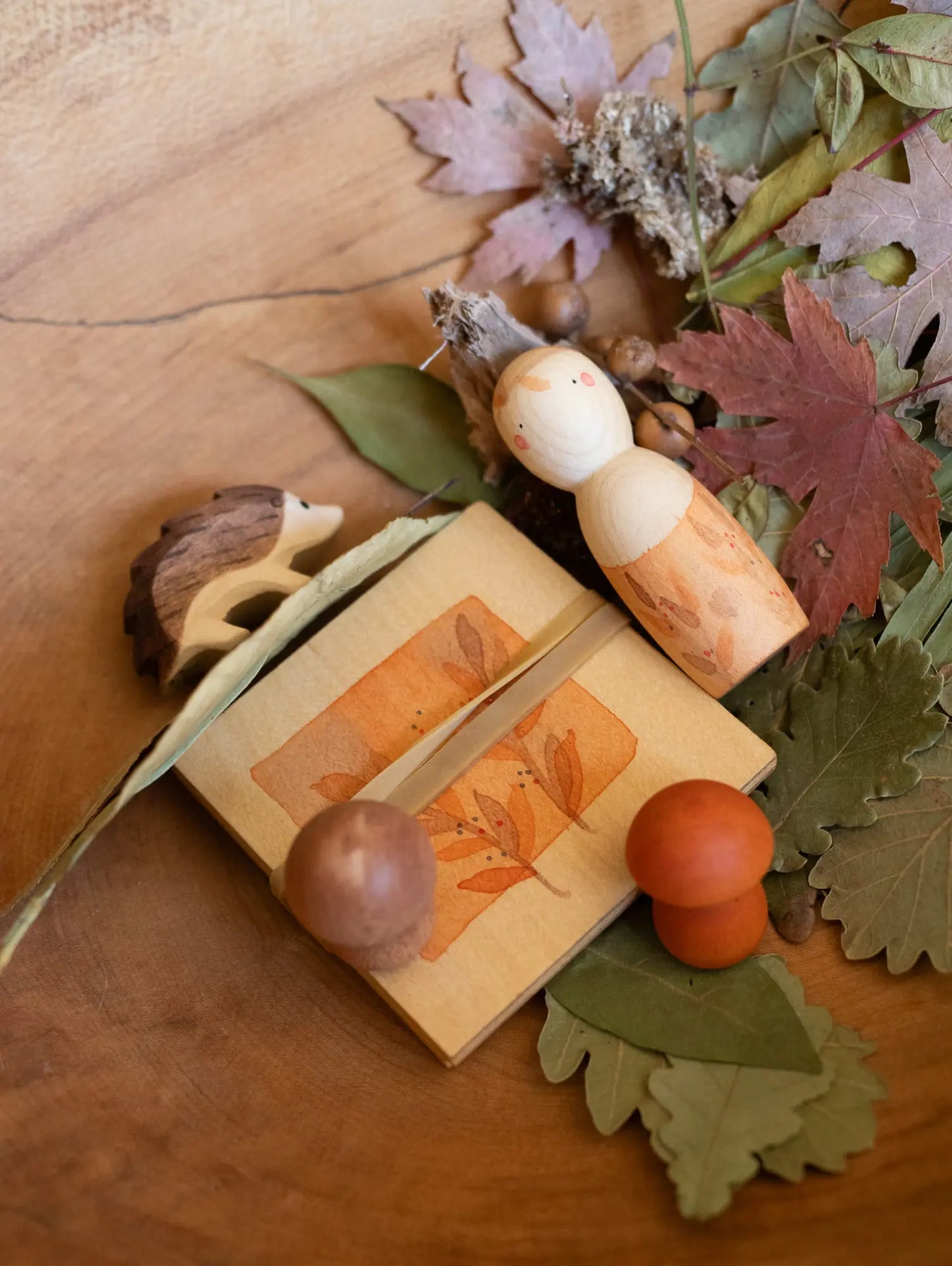 Wooden open-ended toys with autumn-themed elements on a wooden surface
