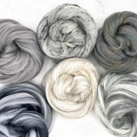 Six skeins of gray and white luxury fiber wool on a light background