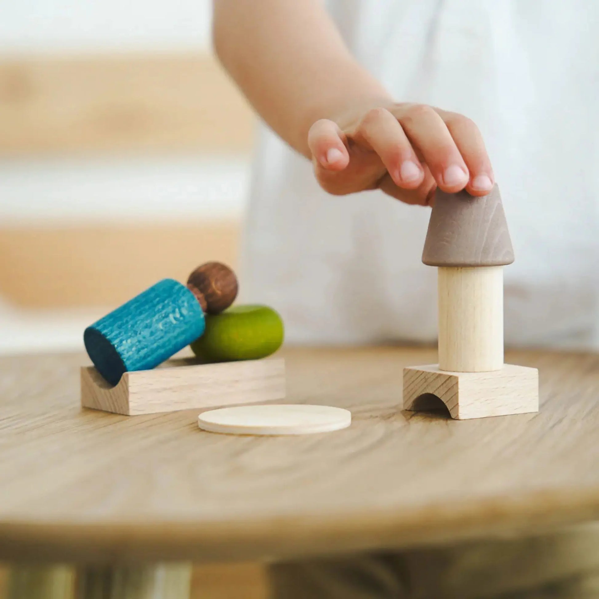 Child's hand interacting with wooden toys on a table