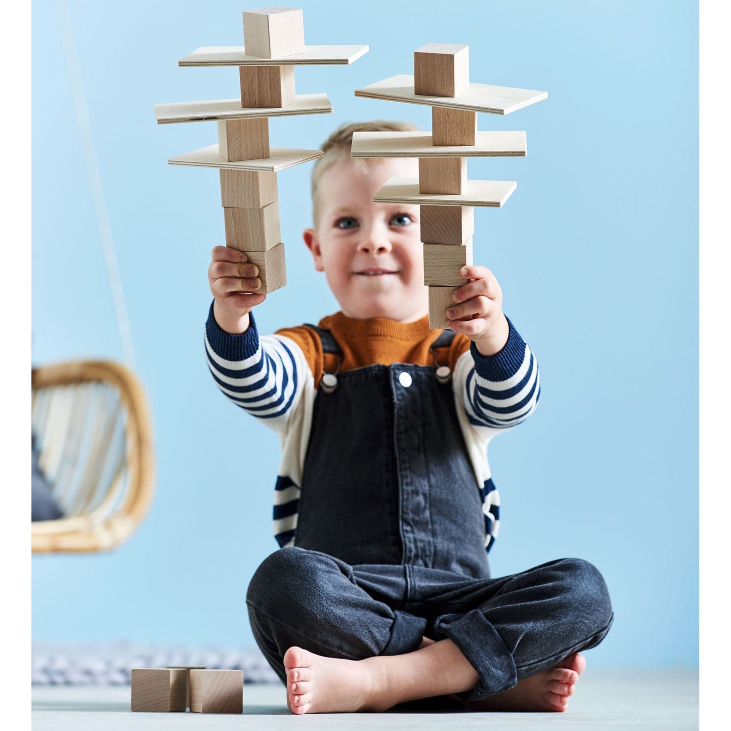 Child playing with wooden blocks against a light blue background