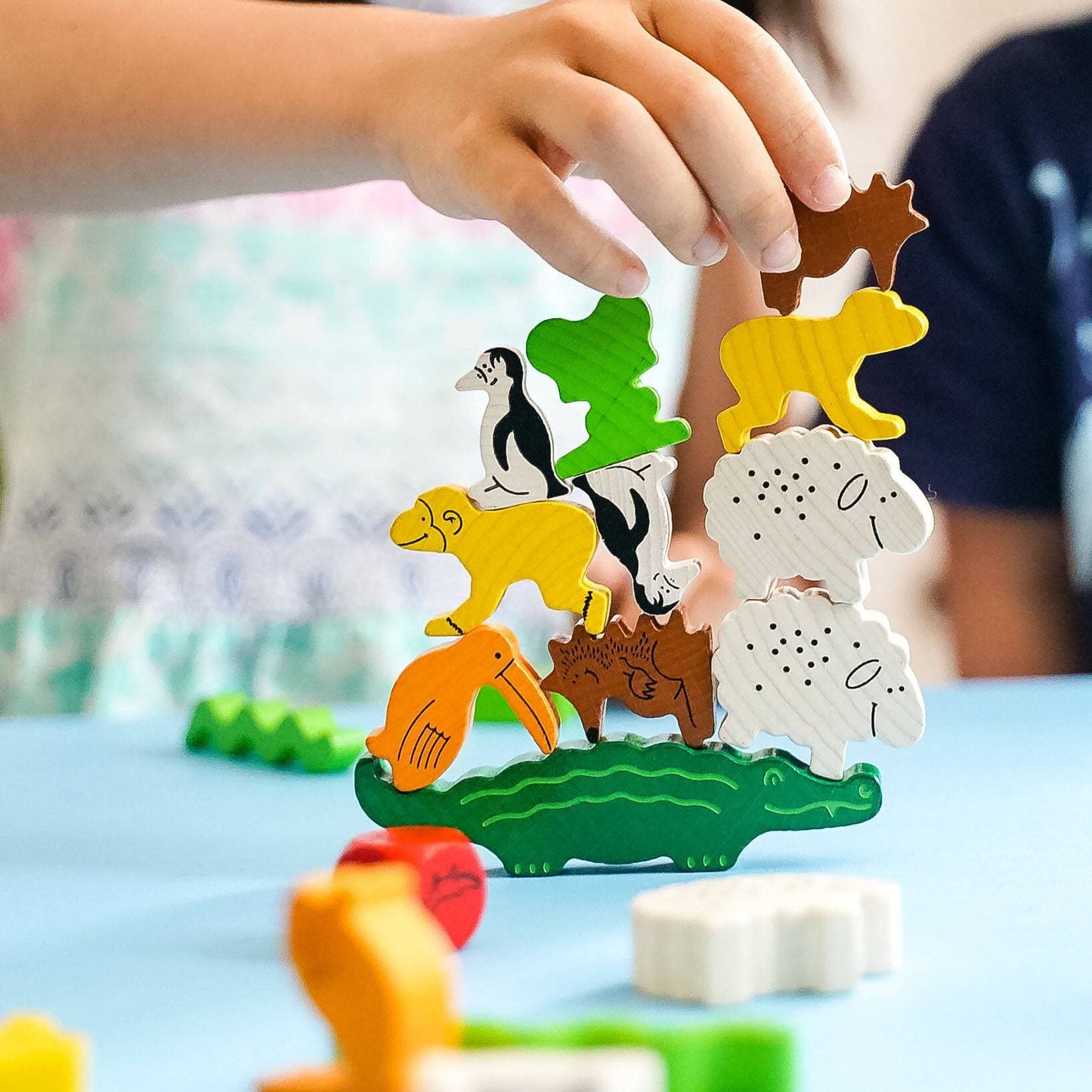 Children's wooden animal puzzle with a hand placing a piece on a blue surface.