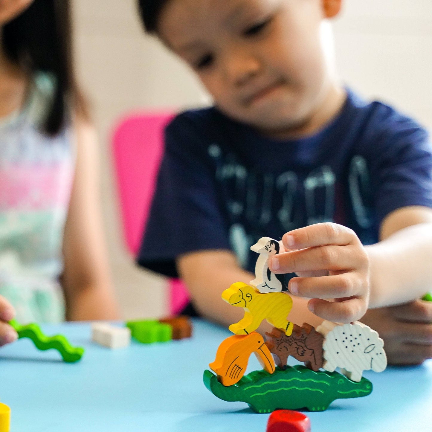 Child playing with colorful animal figurines on a blue surface