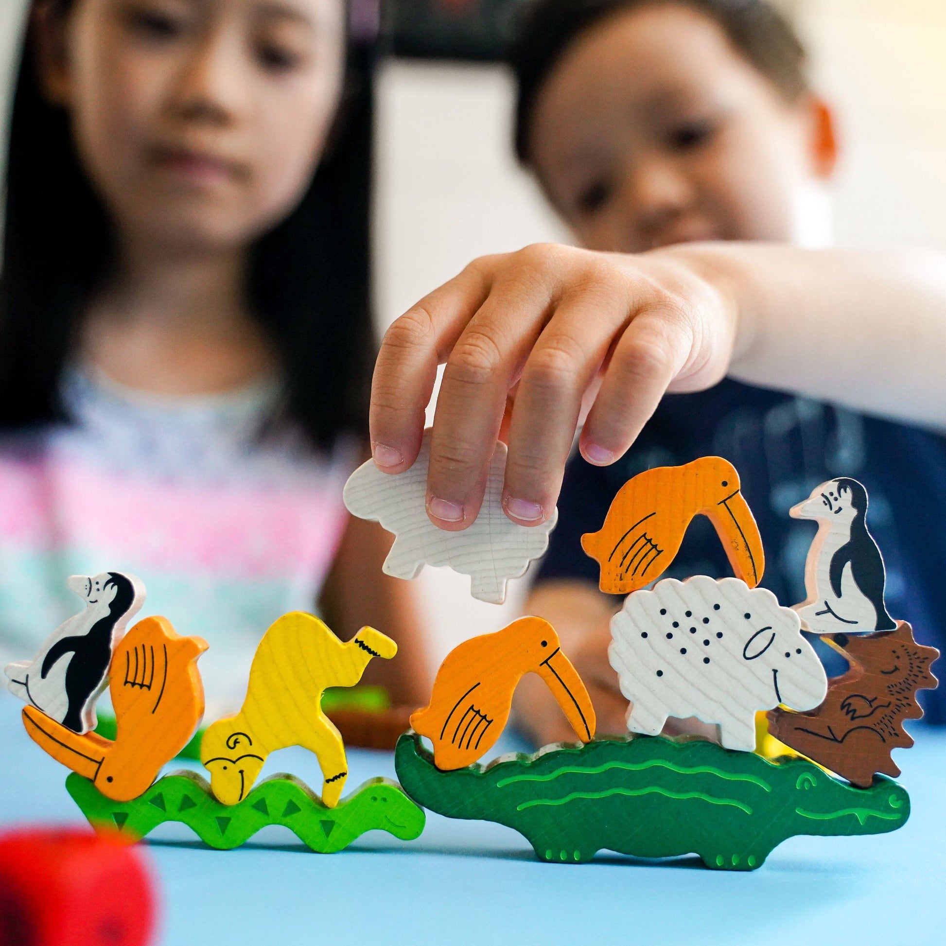 Children playing with colorful animal figurines on a blue surface