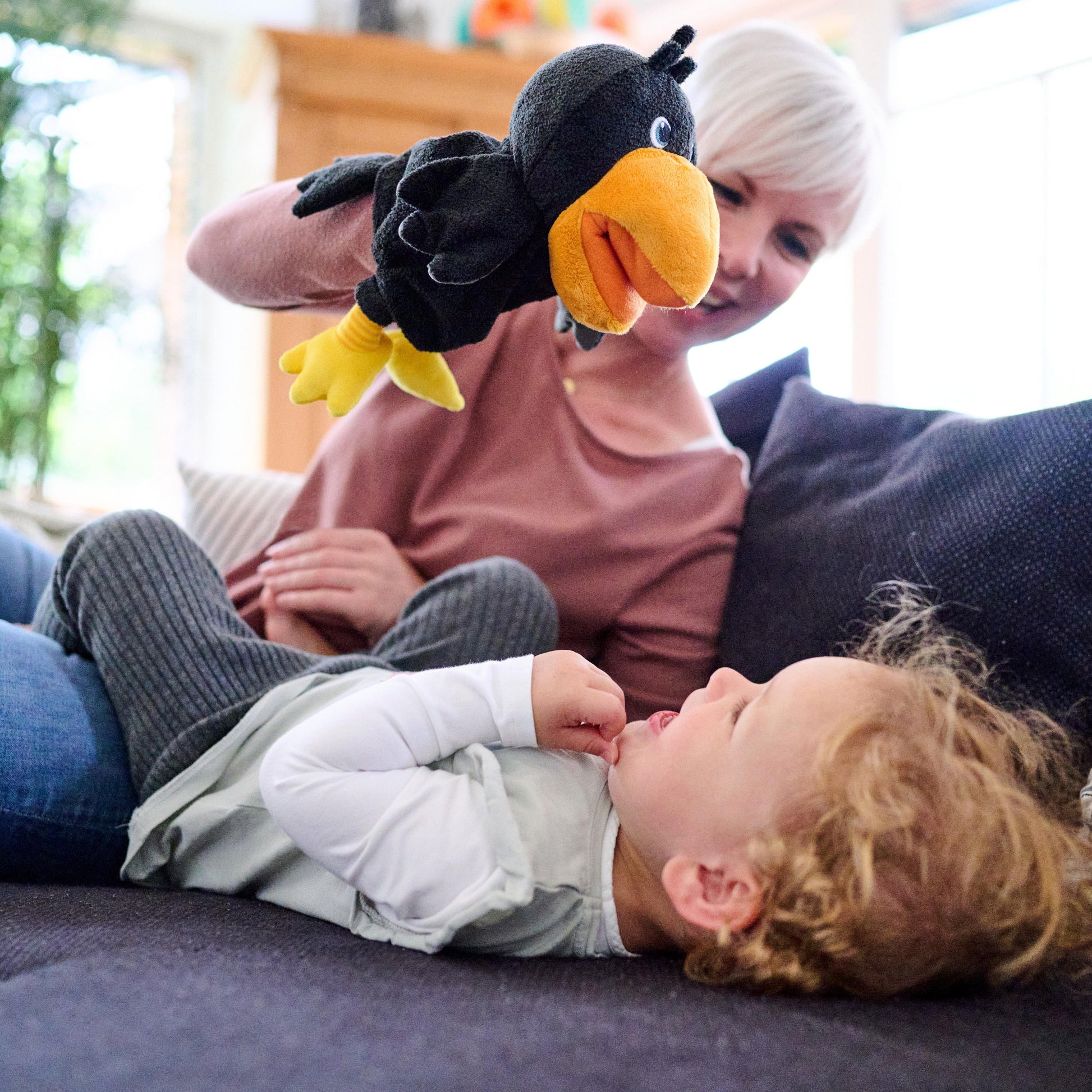 Child playing with a plush toucan toy on a couch