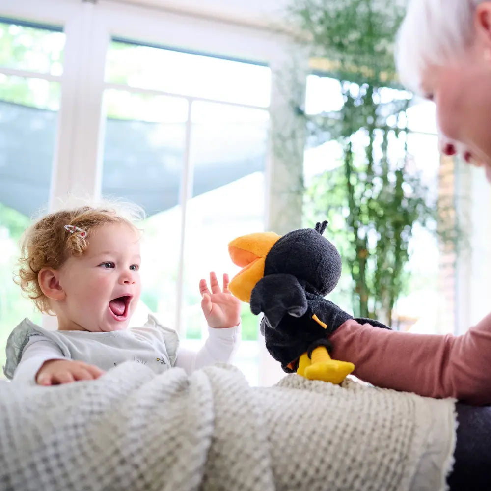 Adult and child playing together with Theo the Raven glove puppet
