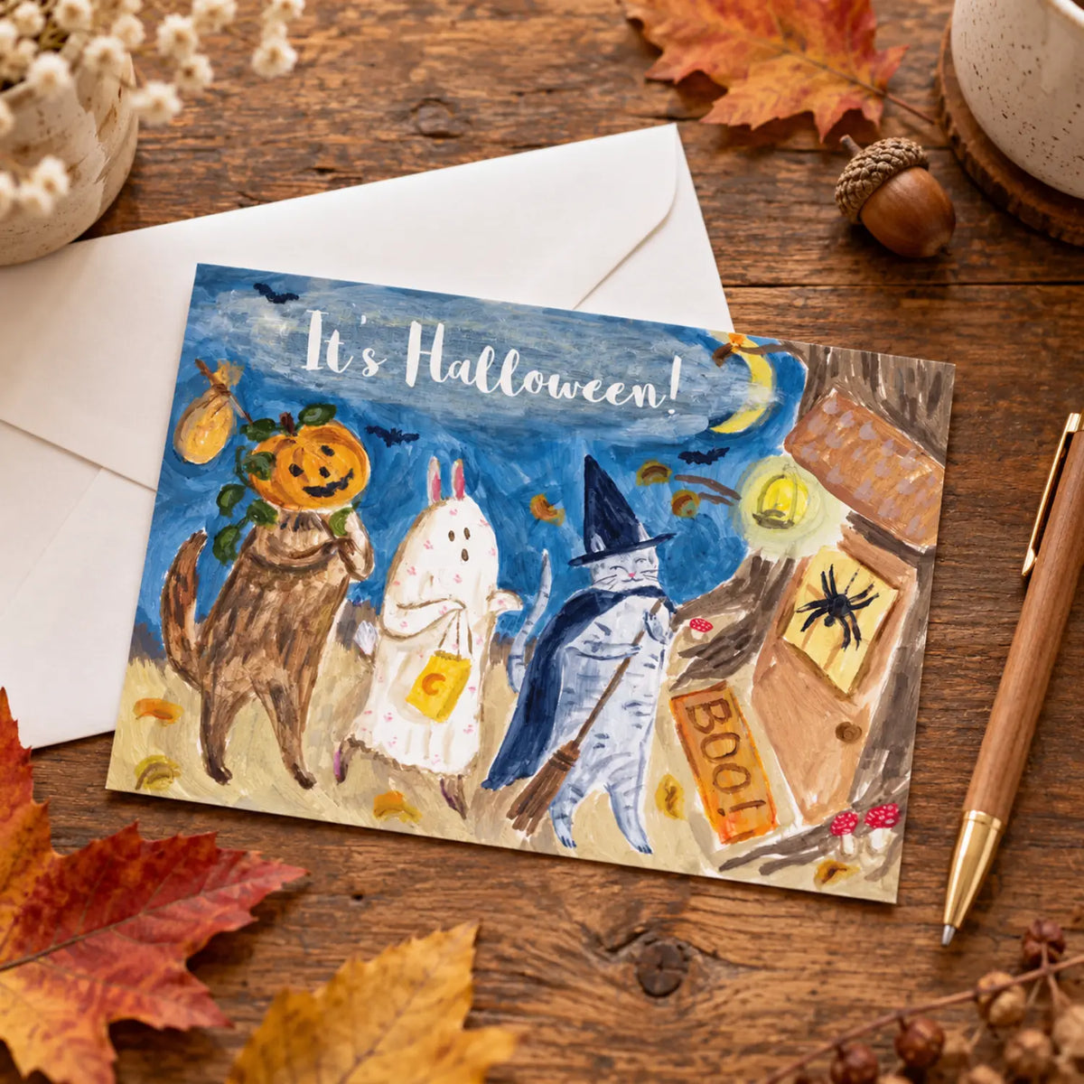 Halloween Parade woodland postcard with costumed trick-or-treating animals styled on an autumn writing desk with a white envelope and pen.