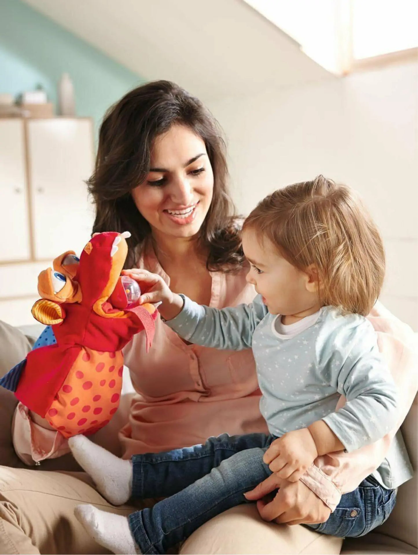 Woman and child playing with a colorful hand puppet on a sofa