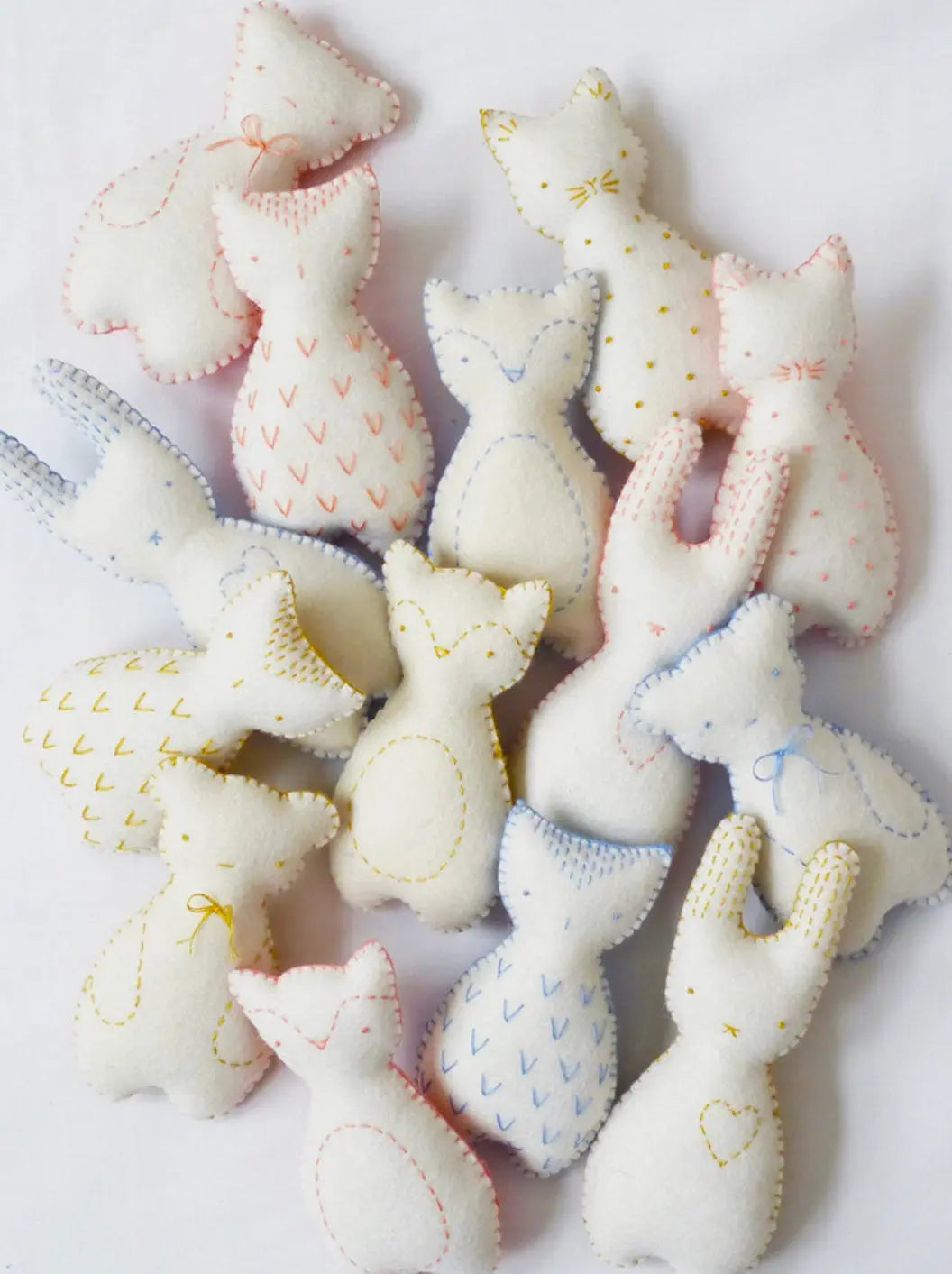 Collection of soft, hand-sewn animal toys on a white background