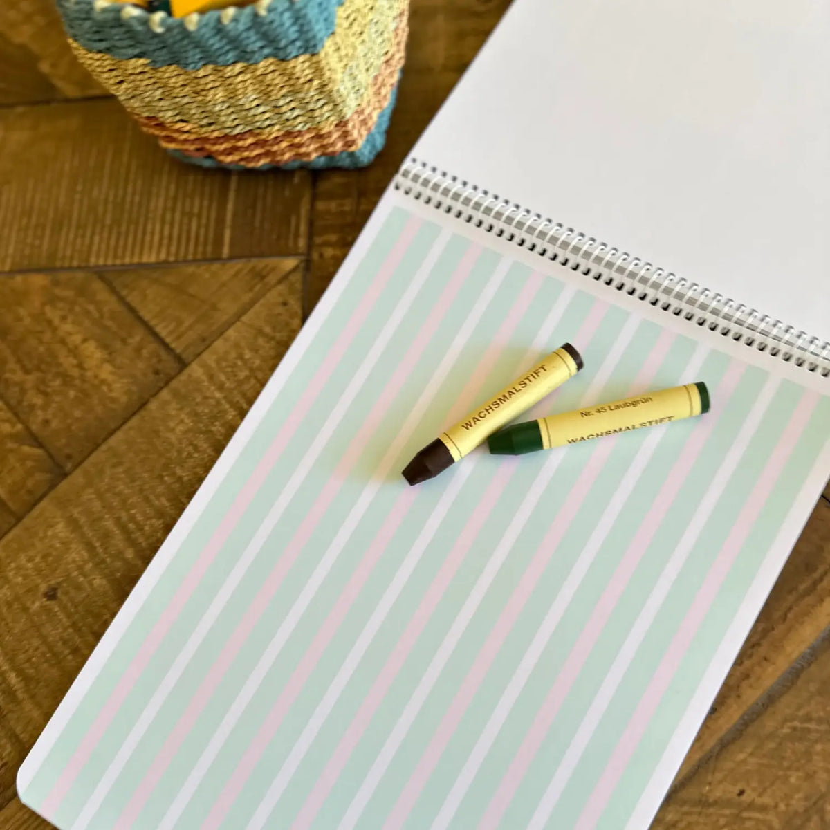 Elementary Book of Centuries open to pastel handwriting lines and a blank page with wax crayons