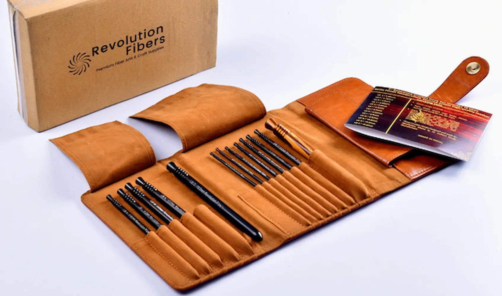 Set of makeup brushes in a brown leather case with Revolution Fibers box on a white background
